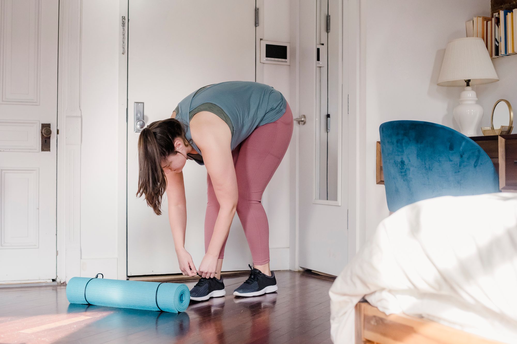 A person tying their shoes at the front door.